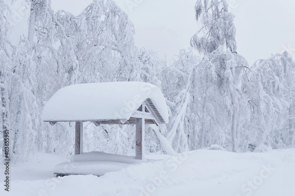 Obraz wooden gazebo with picnic table in a snowdrift after a heavy snowfall in a frosty winter park