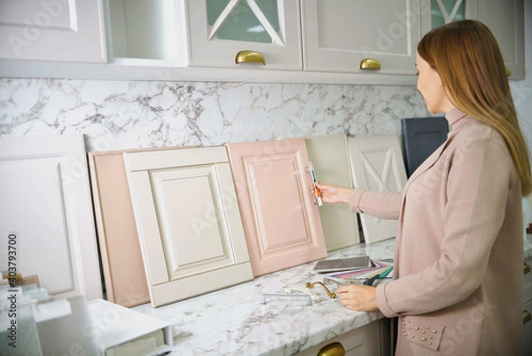 Obraz Home improvement concept. Girl the designer chooses the facades and handles for cabinet furniture in a store showroom. decors boards on the furniture industry. Choosing samples of materials