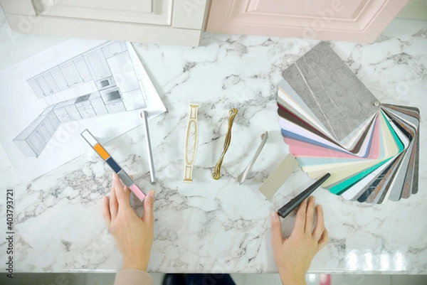 Obraz Home improvement concept. Girl the designer chooses the facades and handles for cabinet furniture in a store showroom. decors boards on the furniture industry. Choosing samples of materials