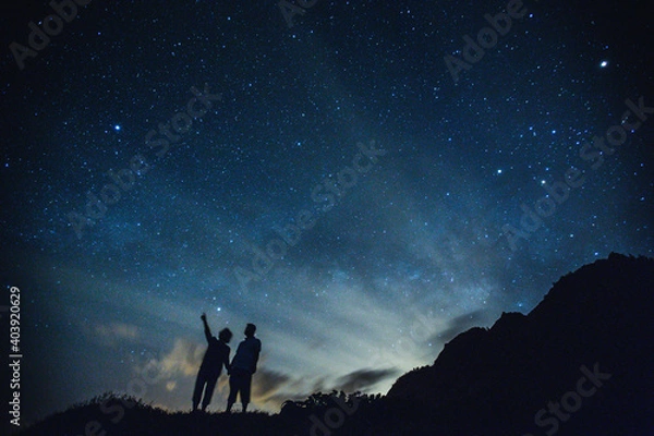 Obraz Silhouette of elderly couple on the hill.  Stargazing at Oahu island, Hawaii. Starry night sky, Milky Way galaxy astrophotography. HONOLULU
