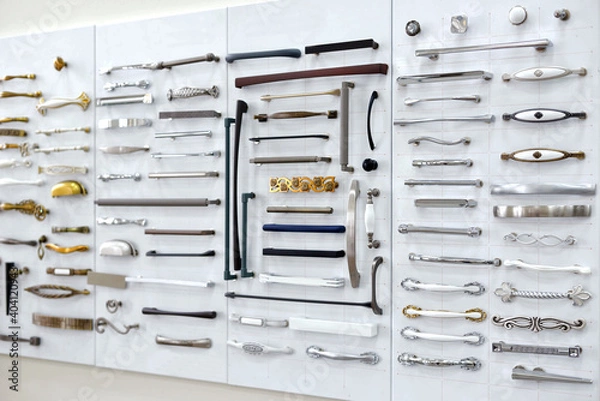 Fototapeta Big selection of handles cabinets parts on a white background shop window. samples of Metal and Stainless Steel handle styles on wooden kitchen cabinet with different Stainless Steel handles