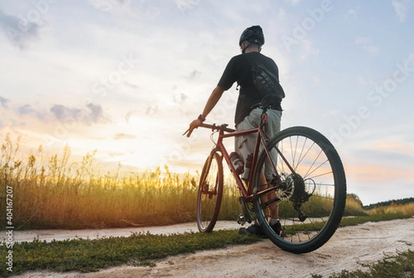 Fototapeta Cyclist in the field enjoying the sunset after sport training.