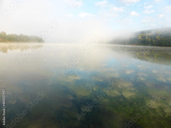 Fototapeta Algae and clouds in the Volga River. And there's a fog over the river
