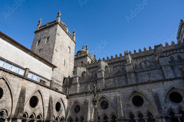 Fototapeta Porto cathedral seen from the inner courtyard. Old cross made of stone in the middle. Building made of stone Blue sky.