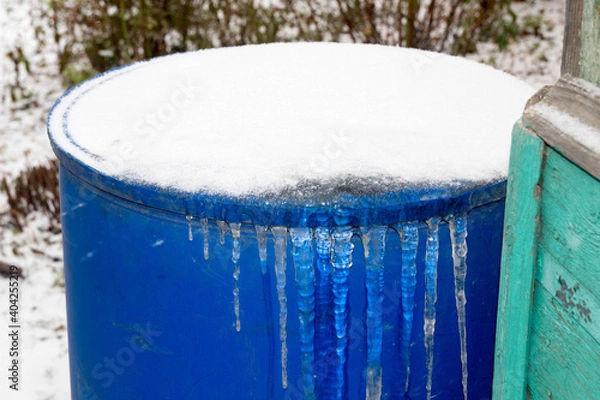Fototapeta blue barrel in the garden with frozen ice with icicles