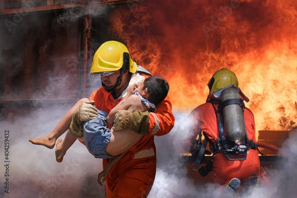 Fototapeta Firefighter holding child boy to save him in fire and smoke,Firemen rescue the boys from fire.