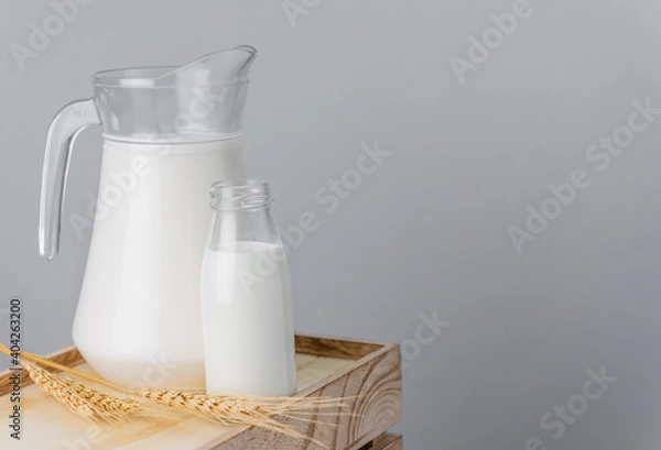 Fototapeta A jug and bottle of  fresh milk glass on wooden crate box..Raw milk is high in calcium and protein to drink for all ages..Milk consumption nutritious and healthy dairy products concept.