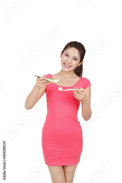Obraz Young woman in pink dress holding toothbrush and toothpaste 