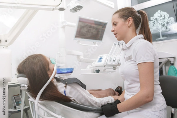 Fototapeta Dentist talking to her patient after putting inhalation sedation face mask on her