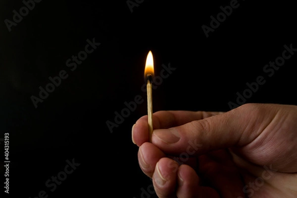 Fototapeta burning match with flame in hand on isolated on black background