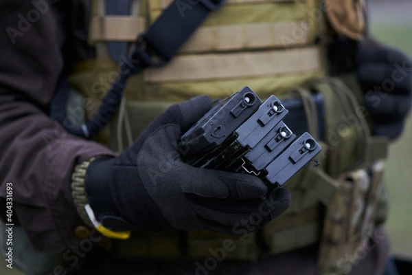 Obraz Airsoft player holds magazines for a machine gun in his hand