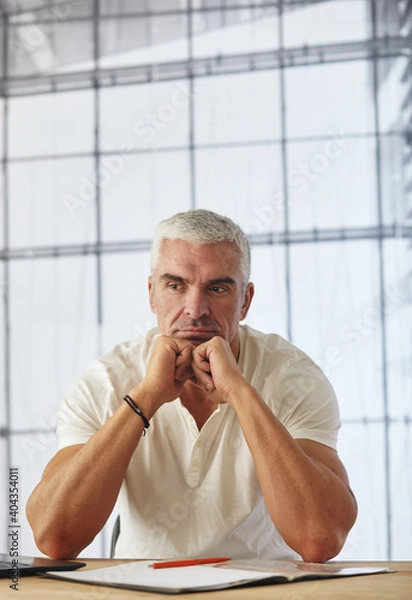 Obraz Portrait of attractive caucasian businessman working on project at office desk with laptop, paperwork. He is thinking