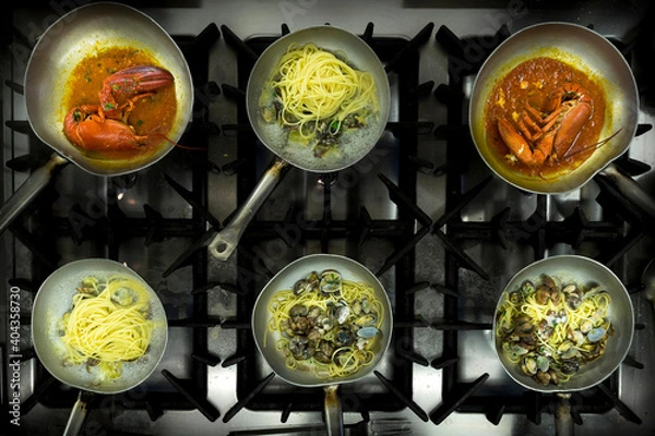 Fototapeta Top view with pans cooking with spaghetti with clams and lobster