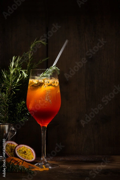 Fototapeta Spritz cocktail with passion fruit, orange and rosemary with ray of light