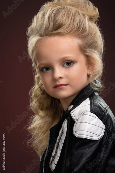Fototapeta portrait of a girl child with beautiful hair and hairstyle in a jacket on a red background