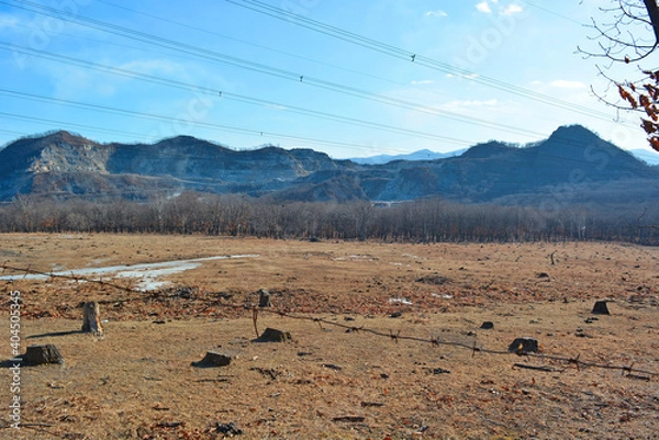 Fototapeta Desert landscape with barbed wire, felled trees, dug mountains