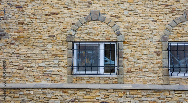 Fototapeta A window with an iron grating in the stone wall.
