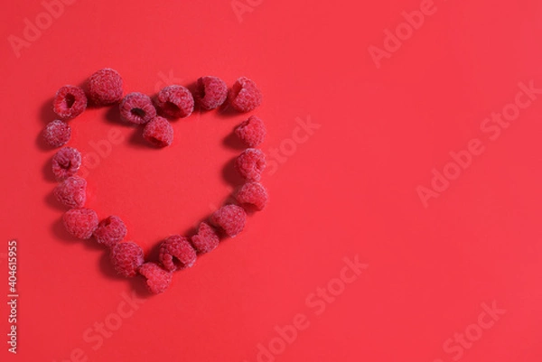 Fototapeta Red heart made from frozen raspberries on a red background. valentine's day convenience food concept.