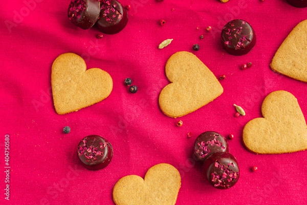 Fototapeta Cinnamon heart cookies background with some chocolates isolated on pink. Valentine's Day concept._