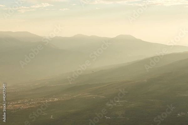 Fototapeta the sun's rays break through the smog on the city located at the foot of the mountains