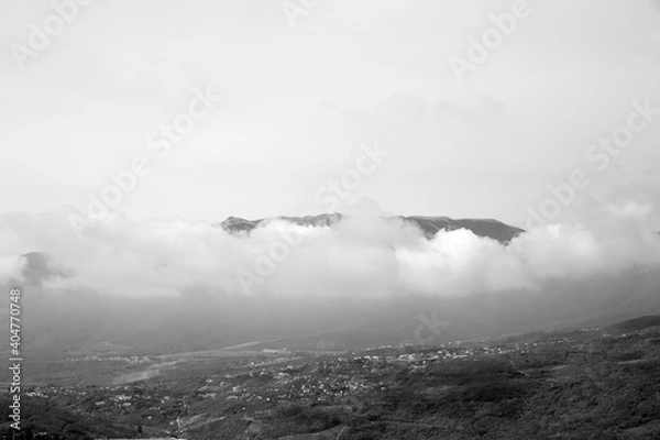 Fototapeta black and white view of the city and the mountain in the clouds