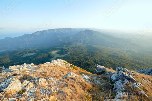 Fototapeta view from the rocky mountain to the forest plain and mountains in the distance