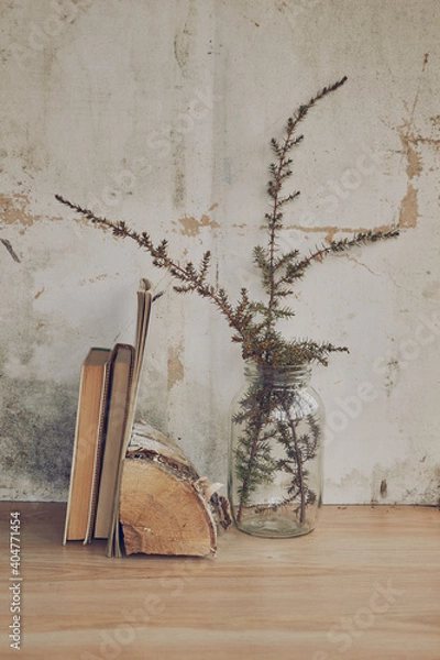 Fototapeta still life in the form of a glass transparent vase with dried grass and books on the background of a vintage wall