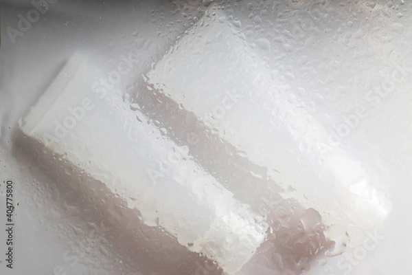 Fototapeta moisturizing skin care products. Face and hand cream under glass surface with water on a white background. spa cosmetic