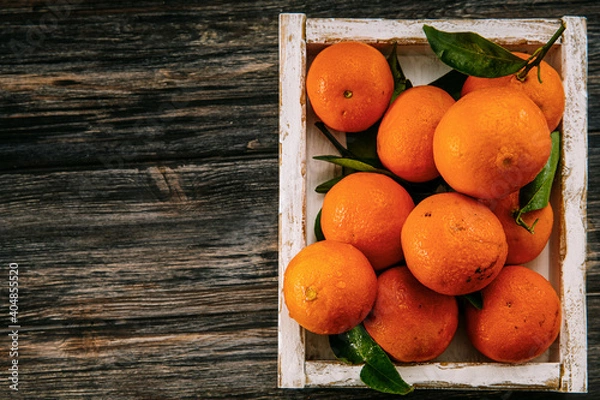Fototapeta Oranges with leaves on a wooden table