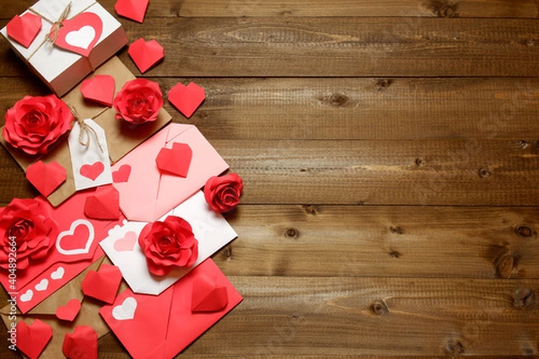 Fototapeta Love, Valentine's, women's day, relations, romantic design with gifts and envelope, wrapped in brown craft paper, tied with twine with bows, labels, handmade paper roses and hearts on wooden boards