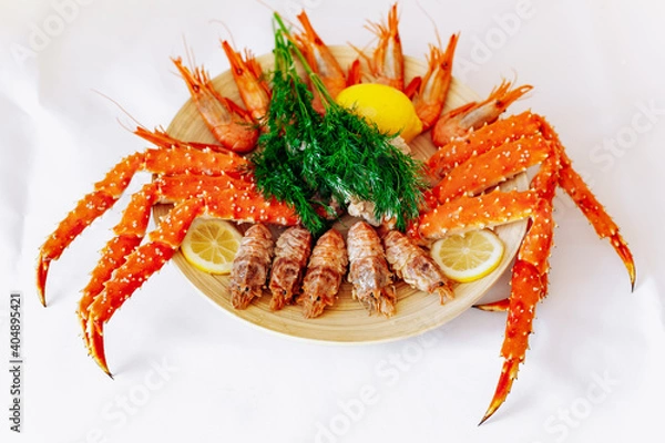 Fototapeta Red king crab and shrimp on a plate with lemon and dill. White background