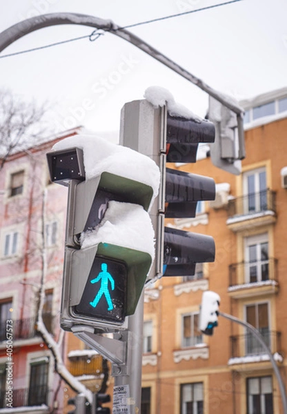 Fototapeta Traffic light with snow on a street in Madrid. The green crosswalk signal is on. Snowing during “Filomena” storm. 