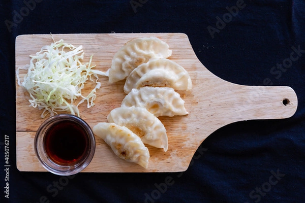 Obraz Japanese grilled gyoza dumplings with soy sauce on a wooden plate.