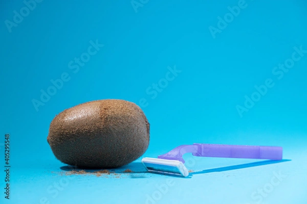 Obraz Shaved kiwi with razor on blue background