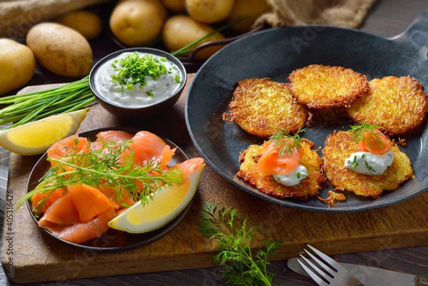 Fototapeta Resche Kartoffelpuffer mit Räucherlachs und Schnittlauchquark in der Eisenpfanne serviert – Crunchy potato pancakes with smoked salmon and chives quark 