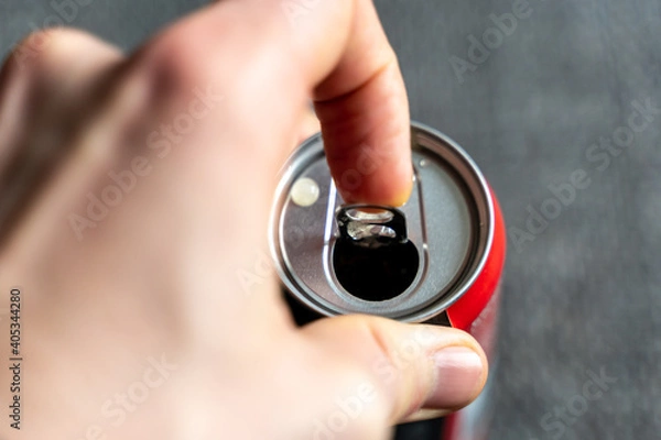 Obraz Pulling the tab of a beverage can with a left male hand. Opening a refreshment drink like cola or energydrink after a hard day.