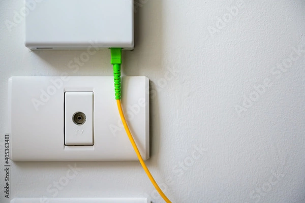 Fototapeta TV socket available on the white wall under fiber optic internet wall box.