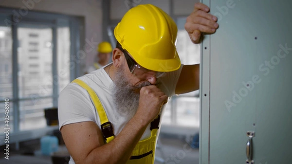 Fototapeta Senior construction worker sick and coughing in renovating apartment