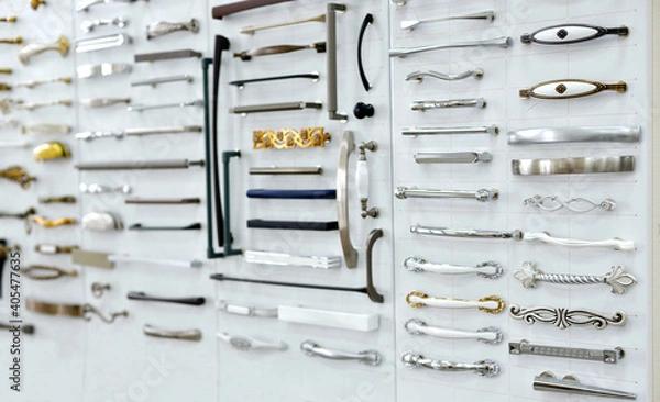 Fototapeta Big selection of handles cabinets parts on a white background shop window. samples of Metal and Stainless Steel handle styles on wooden kitchen cabinet with different Stainless Steel handles