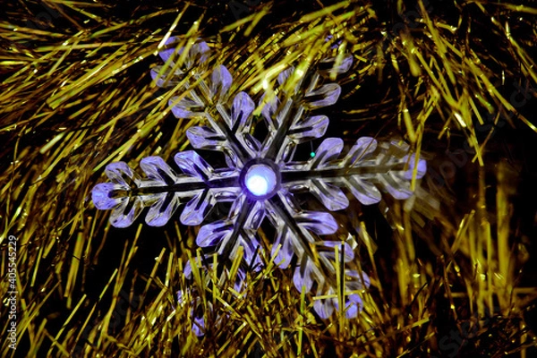 Fototapeta Christmas garland in the form of a snowflake on a golden Christmas tree