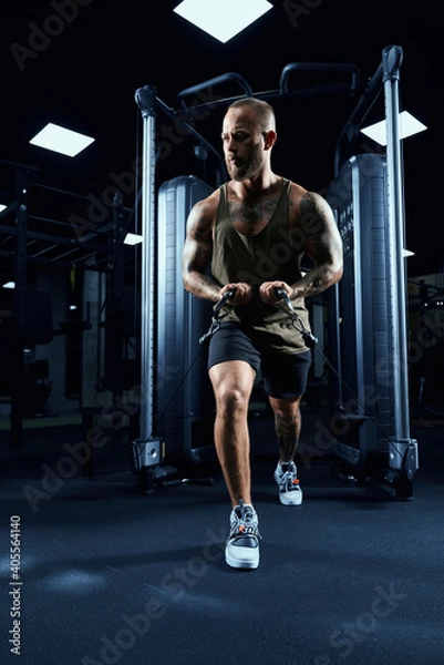 Fototapeta Muscular bodybuilder doing crossover chest exercise.