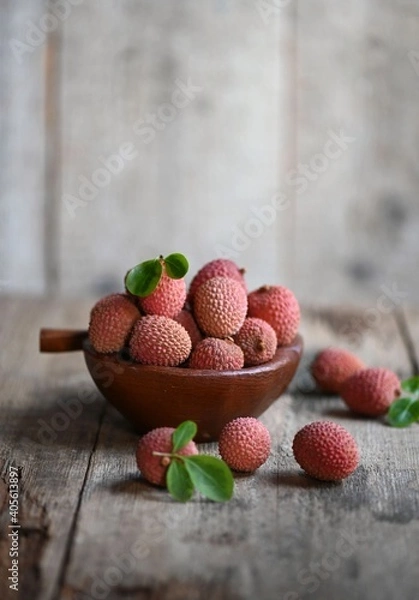 Fototapeta Fresh red lychee fruits.  Fresh organic lychee fruit on a rustic wooden background.