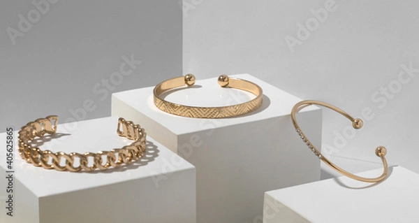 Fototapeta Three golden bracelets on white geometric paper cubes