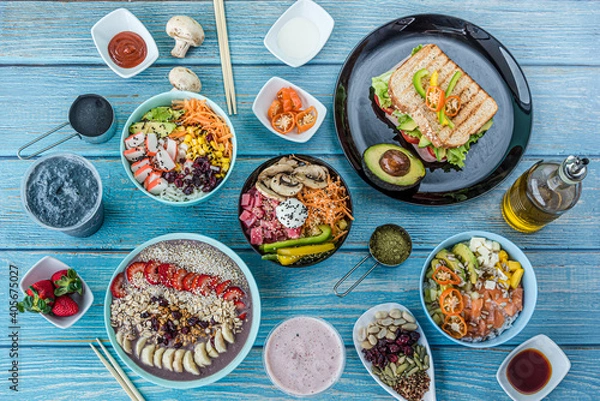Obraz Flat-lay of various kinds of healthy food in plates and bowls on blue wood, top view.