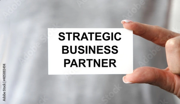 Fototapeta A girl holds a card with a strategic BUSINESS PARTNER.