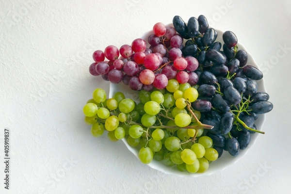 Obraz colorful grapes on a white plate. stock photo
