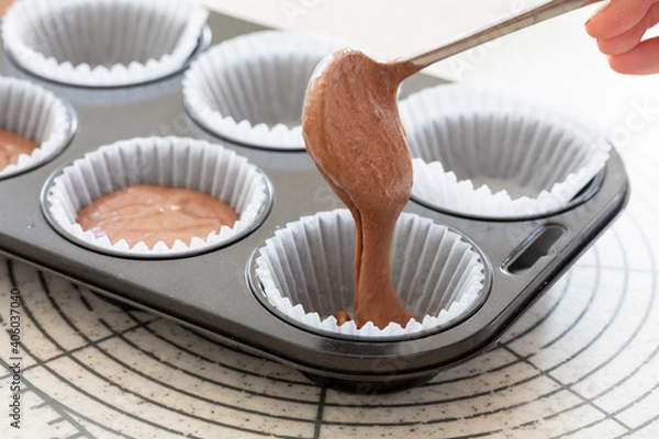 Obraz 自宅でお菓子作り　チョコレートマフィン生地を型に注ぐ様子