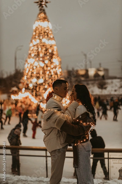 Obraz Young romantic couple in love outdoors in winter before Christmas.  Two lovers are hugging and kissing in Saint Valentine's Day.