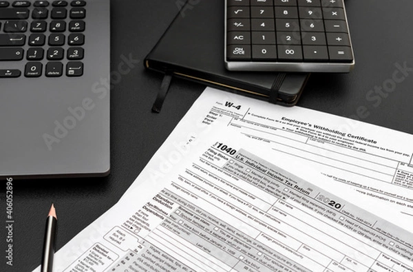 Fototapeta Tax forms with laptop, notepad and calculator on black office desk. Filing tax form.