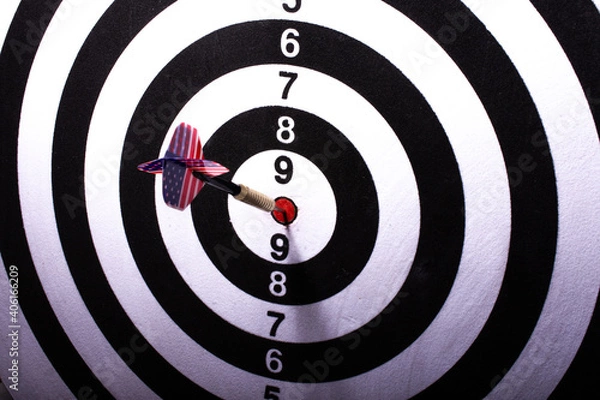 Fototapeta Dart with the flag of the United States of America stuck in the center of black and white target. Selective focus.